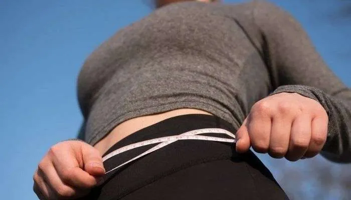 Uma pessoa retirando medida da cintura